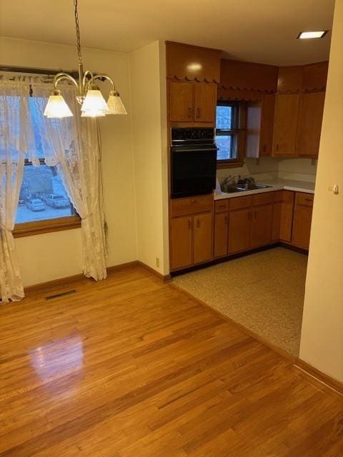 kitchen with pendant lighting, a notable chandelier, light wood-type flooring, and black appliances