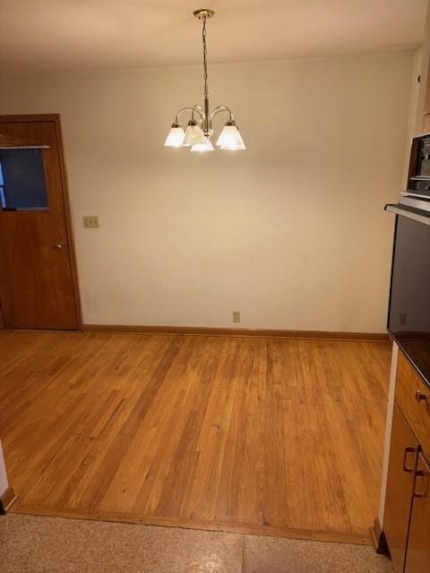 unfurnished dining area with a notable chandelier and light hardwood / wood-style flooring