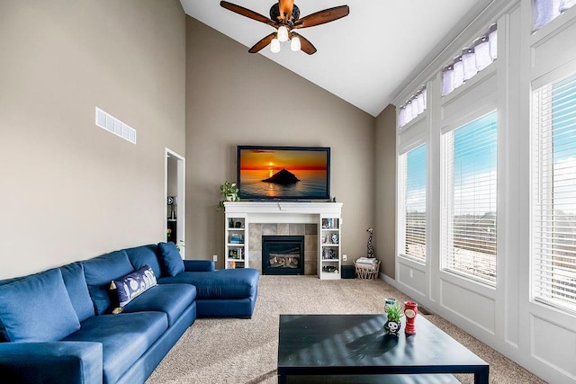 carpeted living room with ceiling fan, high vaulted ceiling, and a tile fireplace