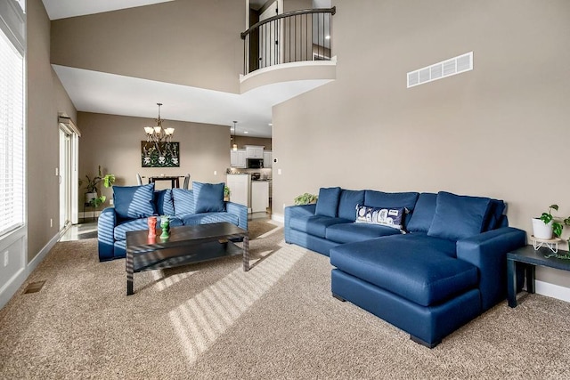 carpeted living room with an inviting chandelier and a towering ceiling