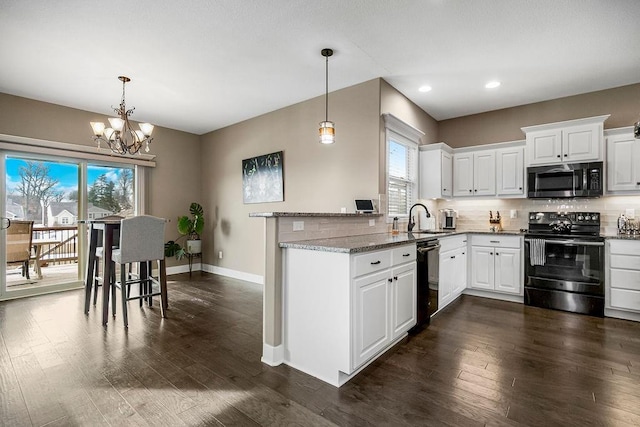 kitchen featuring electric range oven, white cabinets, backsplash, hanging light fixtures, and light stone countertops