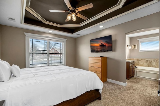 bedroom featuring crown molding, light colored carpet, a tray ceiling, and ensuite bath