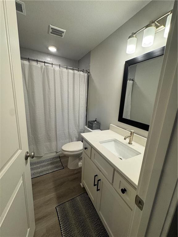 bathroom featuring toilet, hardwood / wood-style flooring, curtained shower, and vanity