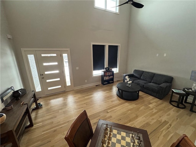 living room with a high ceiling, a healthy amount of sunlight, and light hardwood / wood-style floors