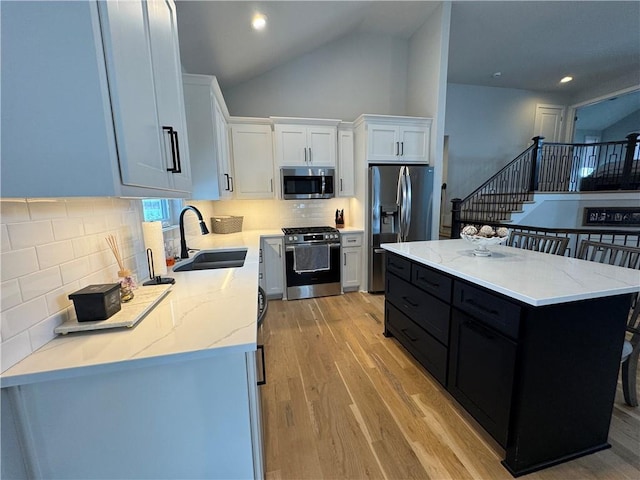 kitchen with appliances with stainless steel finishes, a center island, white cabinets, backsplash, and sink