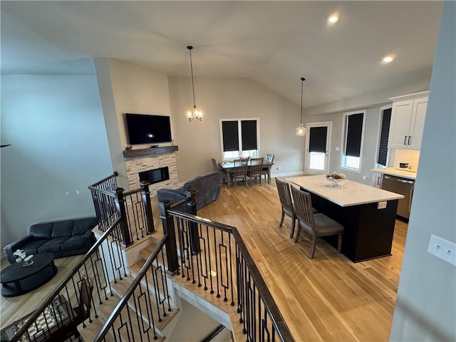 interior space featuring light hardwood / wood-style flooring, an inviting chandelier, lofted ceiling, and a fireplace