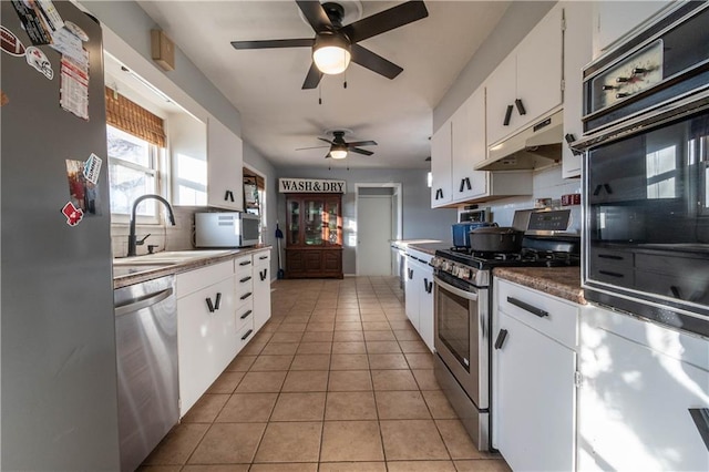 kitchen featuring light tile patterned floors, white cabinetry, ceiling fan, stainless steel appliances, and sink