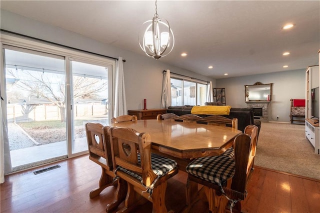 dining space with an inviting chandelier, a fireplace, and wood-type flooring