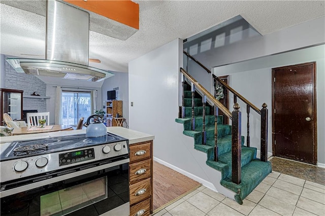 9215 E 85th St, Raytown, MO 64138 - kitchen featuring baseboards, island exhaust hood, light tile patterned floors, a textured ceiling, and stainless steel range with electric cooktop