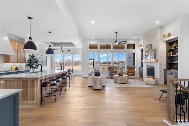 interior space featuring a fireplace, sink, ceiling fan, light wood-type flooring, and built in shelves