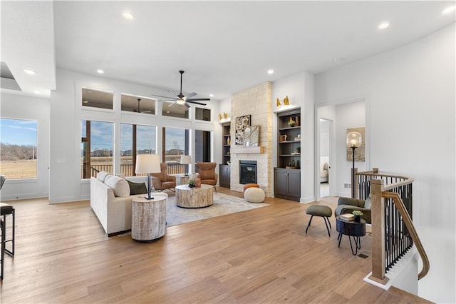 living room with ceiling fan, a wealth of natural light, a fireplace, and light hardwood / wood-style floors