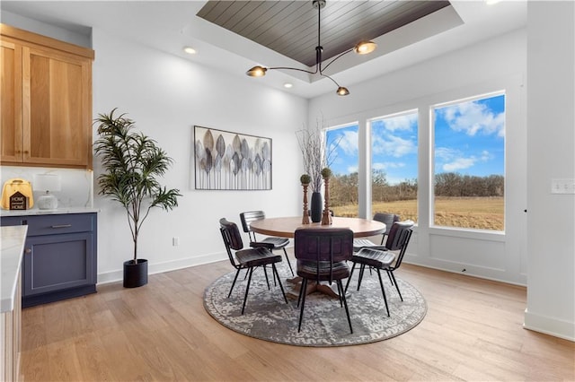 dining area featuring wood ceiling, light hardwood / wood-style floors, and a raised ceiling