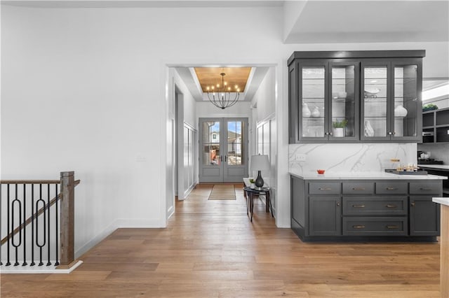 hallway featuring a tray ceiling, a chandelier, and light hardwood / wood-style flooring