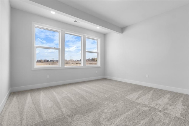 unfurnished room with beamed ceiling and carpet