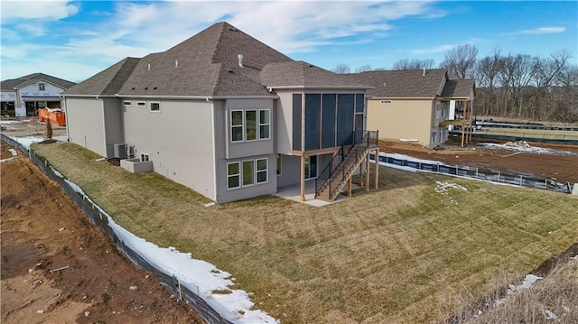 rear view of house featuring a lawn, a sunroom, and a patio area