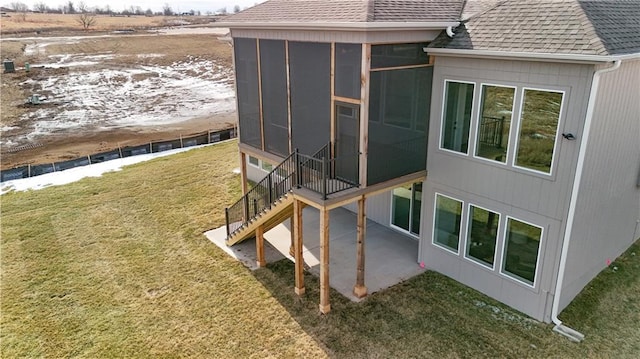 view of side of property with a patio, a sunroom, and a lawn