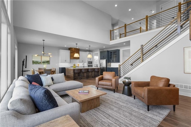 17186 S Heatherwood St, Olathe, KS 66062 - living room featuring a towering ceiling, dark wood-type flooring, stairs, recessed lighting, and a chandelier