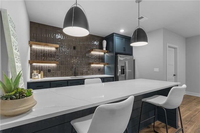 17186 S Heatherwood St, Olathe, KS 66062 - bar area with stainless steel fridge with ice dispenser, a sink, decorative backsplash, wood finished floors, and pendant lighting
