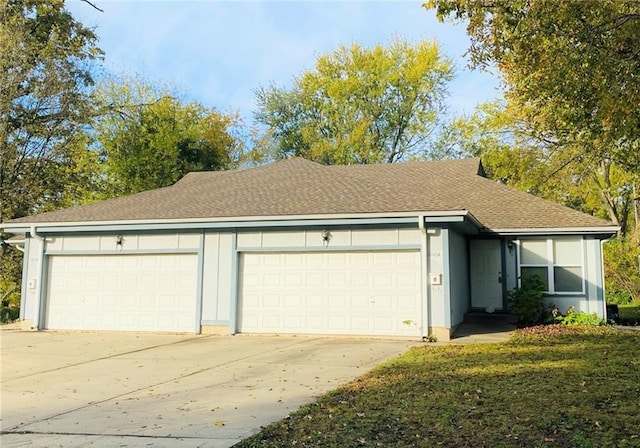 ranch-style home with an attached garage, driveway, and roof with shingles