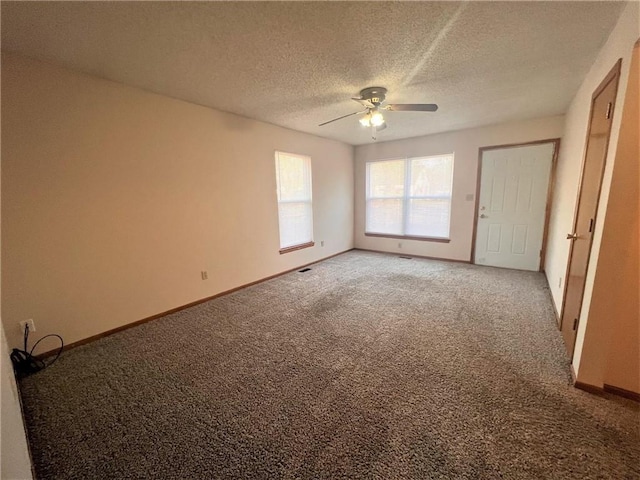 empty room featuring light colored carpet, a textured ceiling, baseboards, and ceiling fan