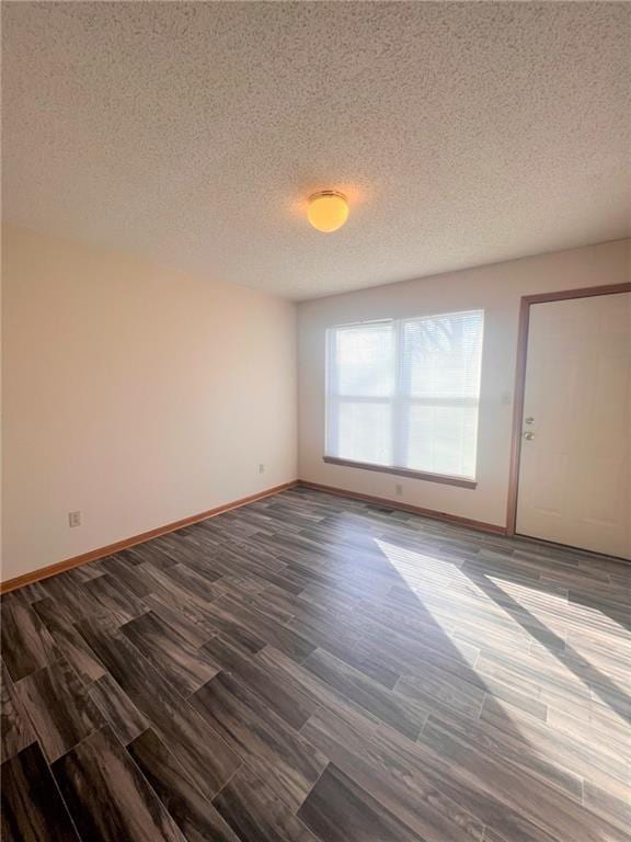 unfurnished room with dark wood finished floors, baseboards, and a textured ceiling