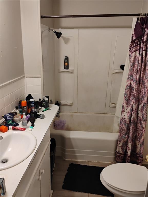 full bathroom featuring toilet, tile walls, vanity, and shower / tub combo with curtain