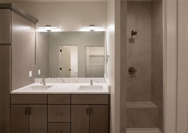 full bathroom with a sink, double vanity, and a tile shower