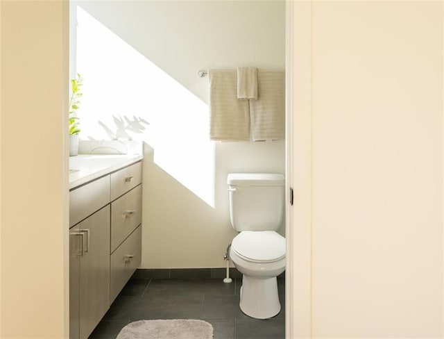 bathroom featuring baseboards, toilet, vanity, and tile patterned flooring