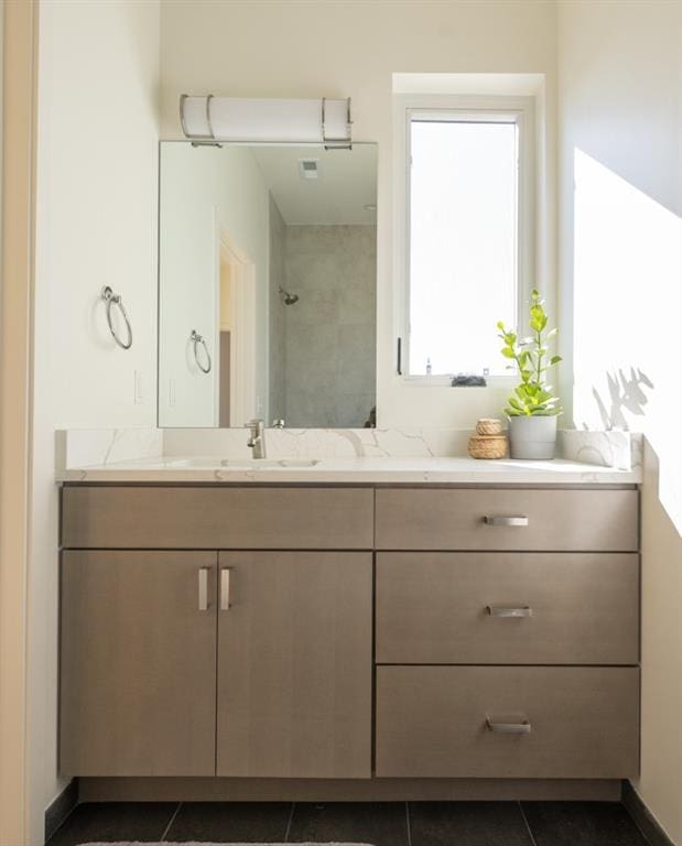 bathroom featuring vanity, tile patterned floors, and a tile shower