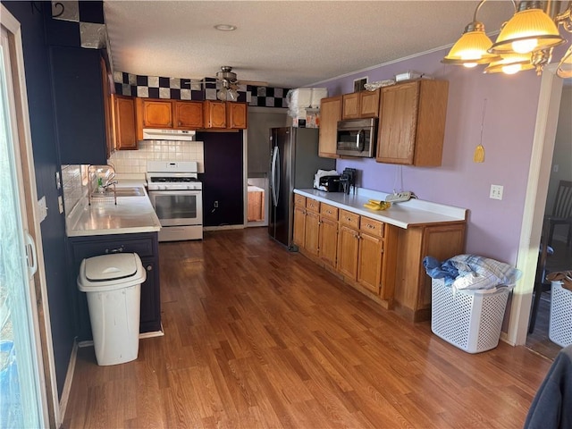 kitchen with sink, backsplash, hanging light fixtures, white gas stove, and fridge