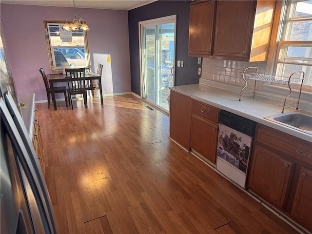 kitchen with dishwasher, an inviting chandelier, decorative backsplash, sink, and hanging light fixtures