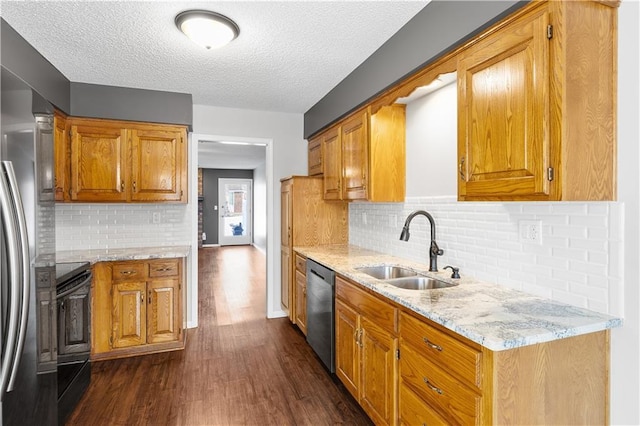 kitchen with sink, dark wood-type flooring, light stone counters, a textured ceiling, and stainless steel appliances