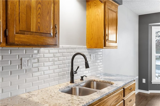 kitchen with sink, decorative backsplash, a textured ceiling, and light stone counters