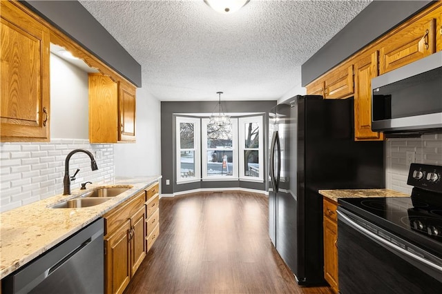 kitchen featuring pendant lighting, stainless steel appliances, decorative backsplash, sink, and light stone counters