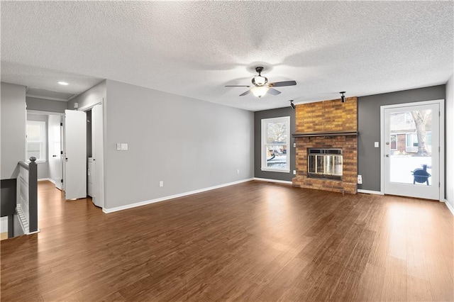 unfurnished living room with a textured ceiling, dark wood-type flooring, and a fireplace