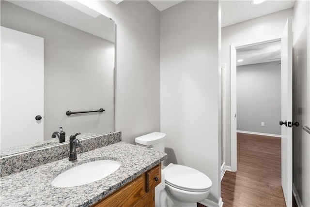 bathroom with hardwood / wood-style flooring, toilet, and vanity