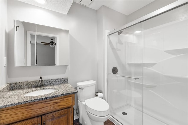 bathroom with vanity, toilet, ceiling fan, and a shower with door