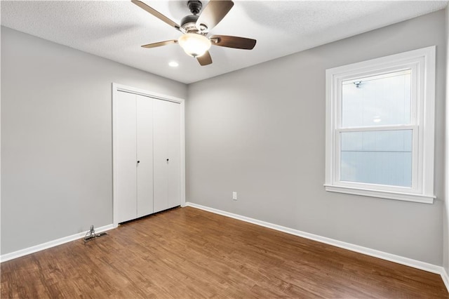 unfurnished bedroom featuring a closet, ceiling fan, a textured ceiling, and wood-type flooring