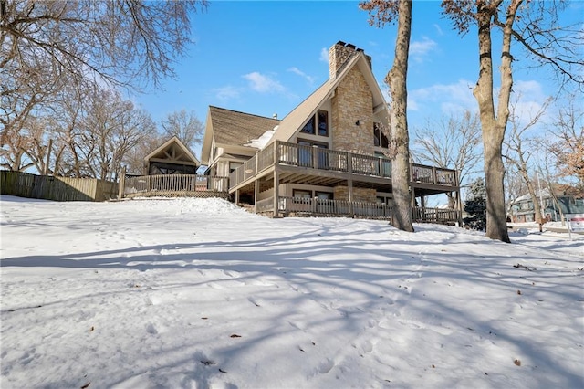 snow covered back of property featuring a wooden deck