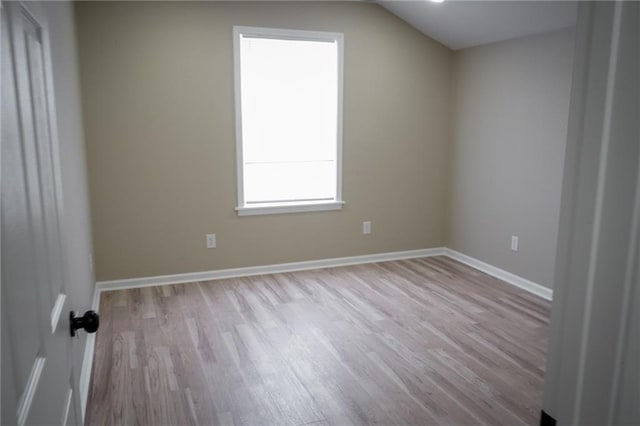 spare room with light hardwood / wood-style floors and lofted ceiling