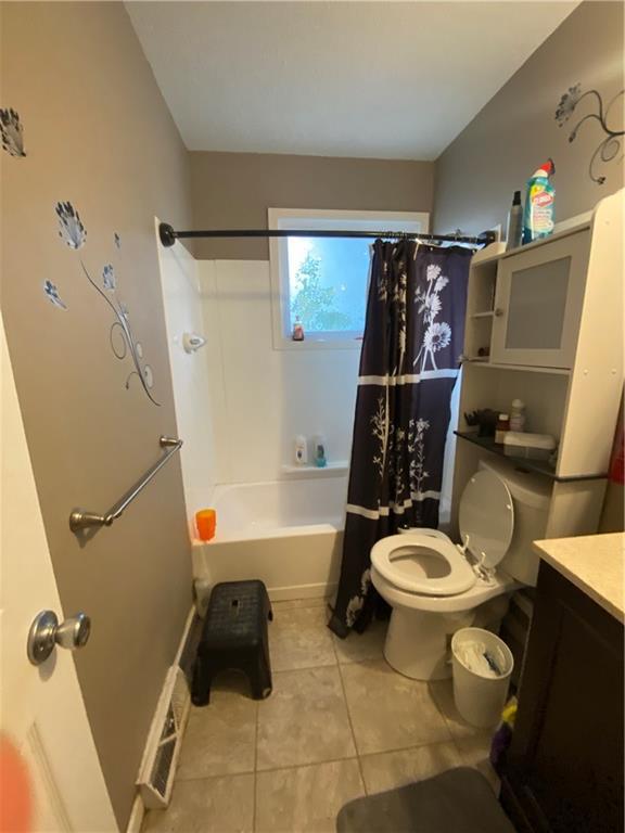 full bathroom with shower / bath combo with shower curtain, toilet, vanity, and tile patterned flooring