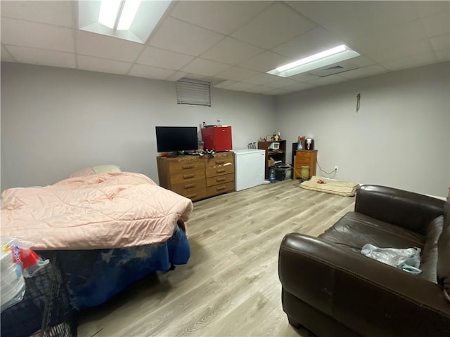 bedroom featuring a paneled ceiling, refrigerator, and light wood finished floors