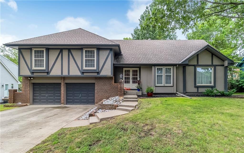 english style home featuring a front yard, french doors, and a garage