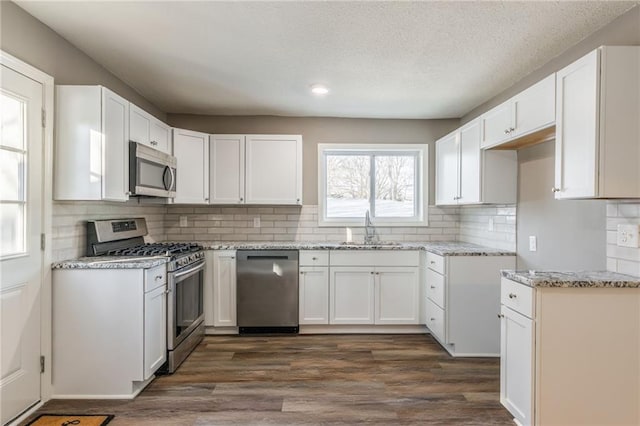 kitchen featuring decorative backsplash, sink, stainless steel appliances, white cabinets, and dark hardwood / wood-style flooring