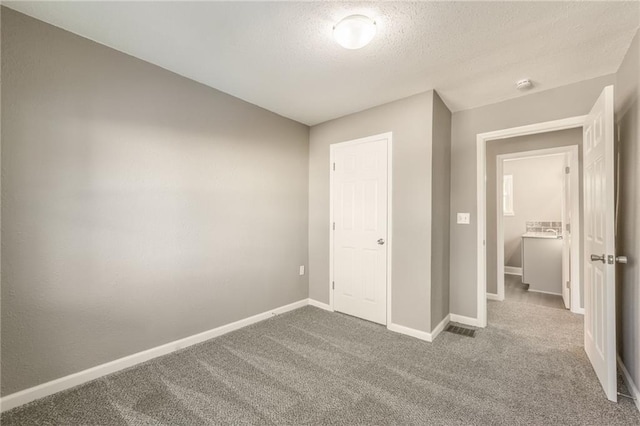 unfurnished bedroom featuring a closet, a textured ceiling, and carpet flooring