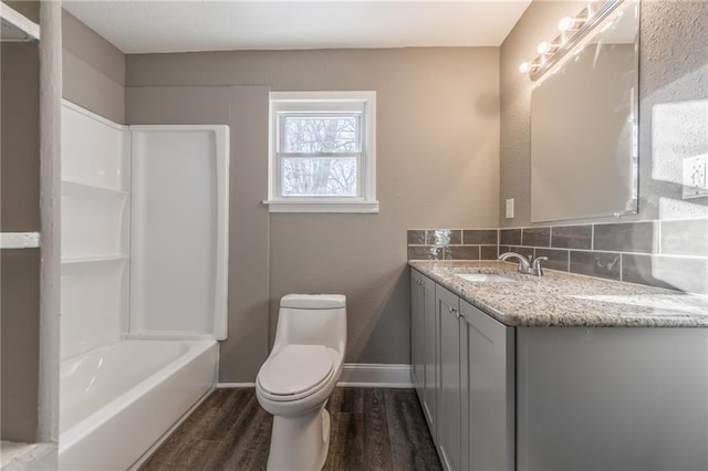 full bathroom featuring toilet, tasteful backsplash, shower / bathing tub combination, wood-type flooring, and vanity