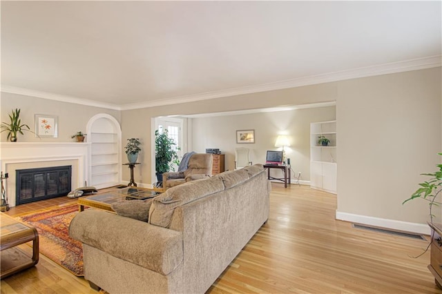 living room featuring ornamental molding, light hardwood / wood-style flooring, and built in shelves