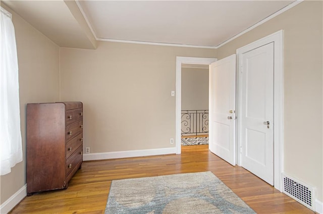 unfurnished bedroom featuring crown molding and light wood-type flooring