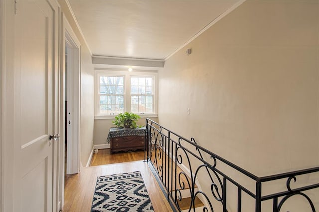 corridor with ornamental molding and light wood-type flooring