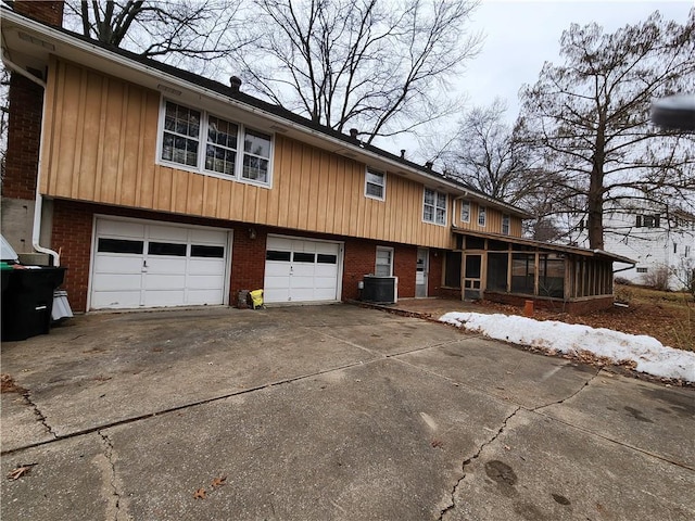 view of front of property featuring a garage, a sunroom, and cooling unit